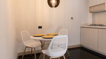 A modern dining area with a round table, white chairs, and pendant lighting.