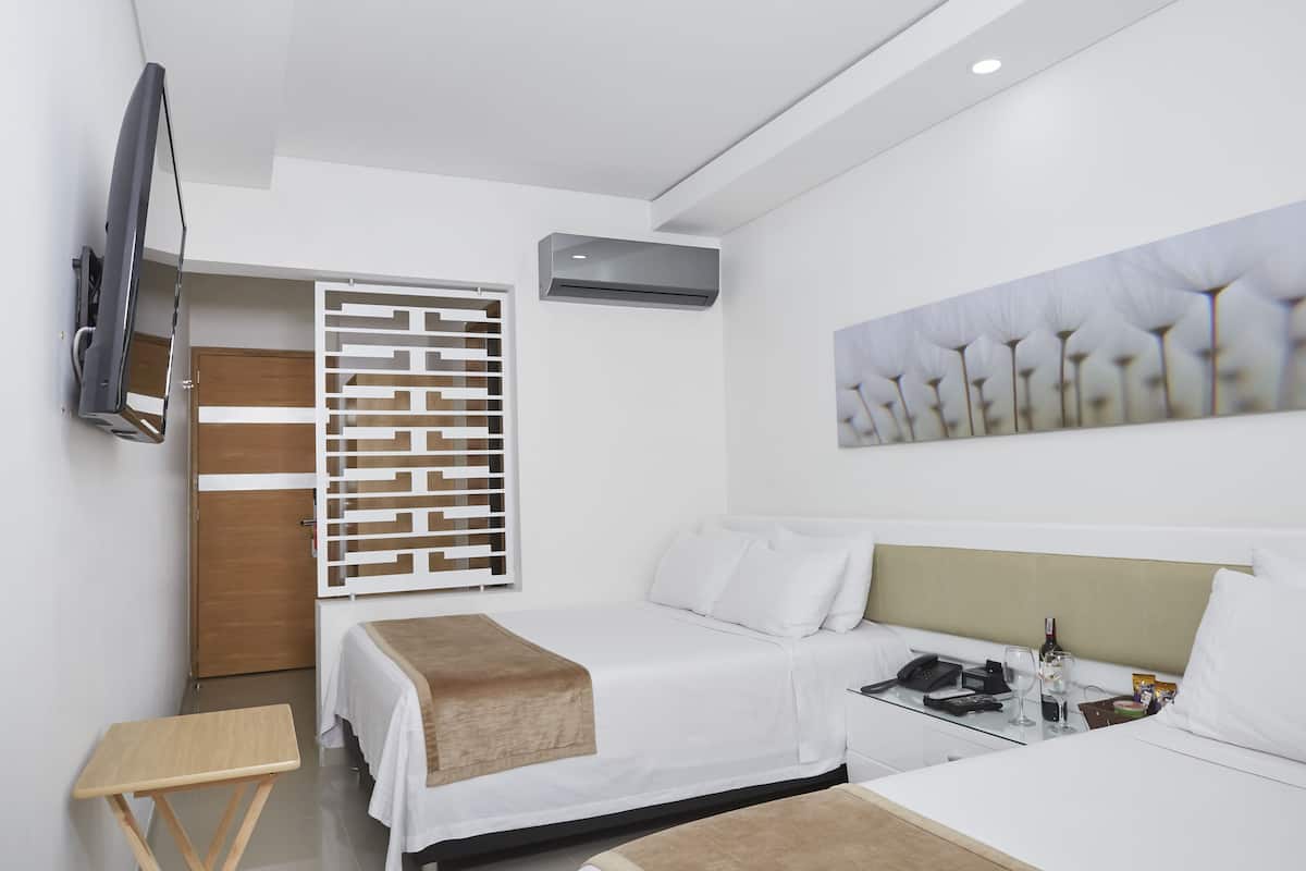 Una habitación de hotel moderna con cama, mesita de noche, televisor, equipo de aire acondicionado y un adorno en la pared.