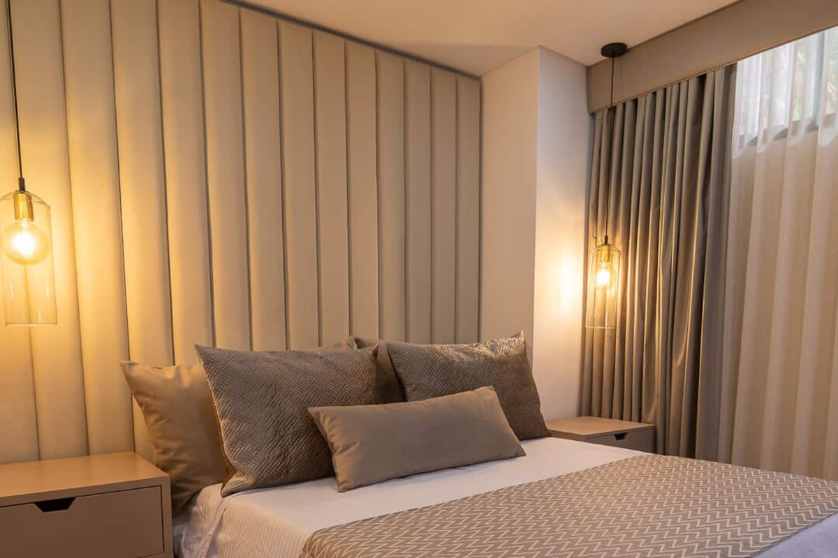 Un dormitorio moderno con una cama grande, una mesita de noche y una lámpara fijada a la pared.