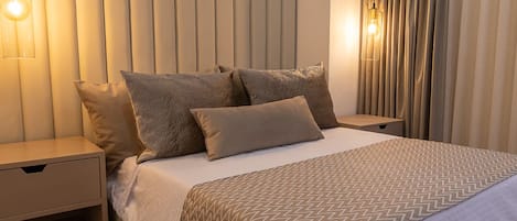 A modern bedroom with a large bed, a nightstand, and a wall-mounted light fixture.