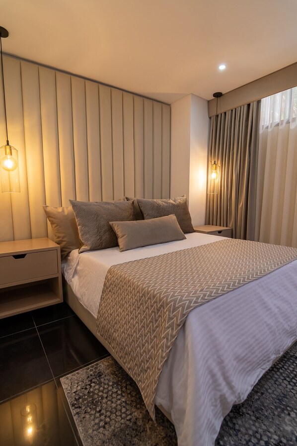 Une chambre moderne avec un grand lit, une table de chevet et un luminaire fixé au mur.