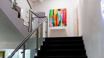 A staircase with glass railings and a colorful abstract painting on the wall.