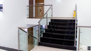 A modern staircase with glass railings and a fire extinguisher on the wall.
