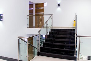 A modern staircase with glass railings and a fire extinguisher on the wall.
