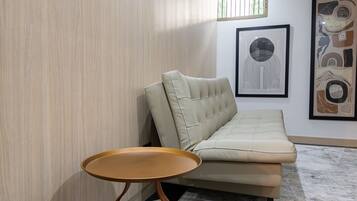 A modern living room with a sofa, a small round table, and a cat bed.