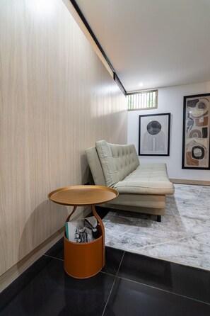 Un salon moderne avec un canapé, une petite table ronde et un panier pour chat.