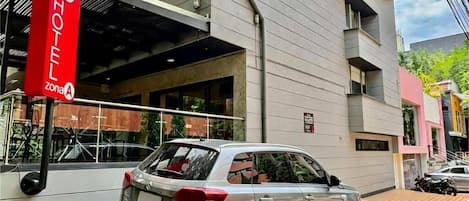 A hotel with a modern facade, a parked car, and a clear sky.