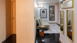 A modern hallway with a wooden wardrobe, a sofa, and a small table with a basket. - Hotel Zona A (Medellín)