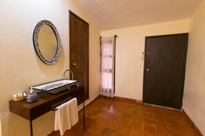 Un baño con lavamanos, espejo y toallero.