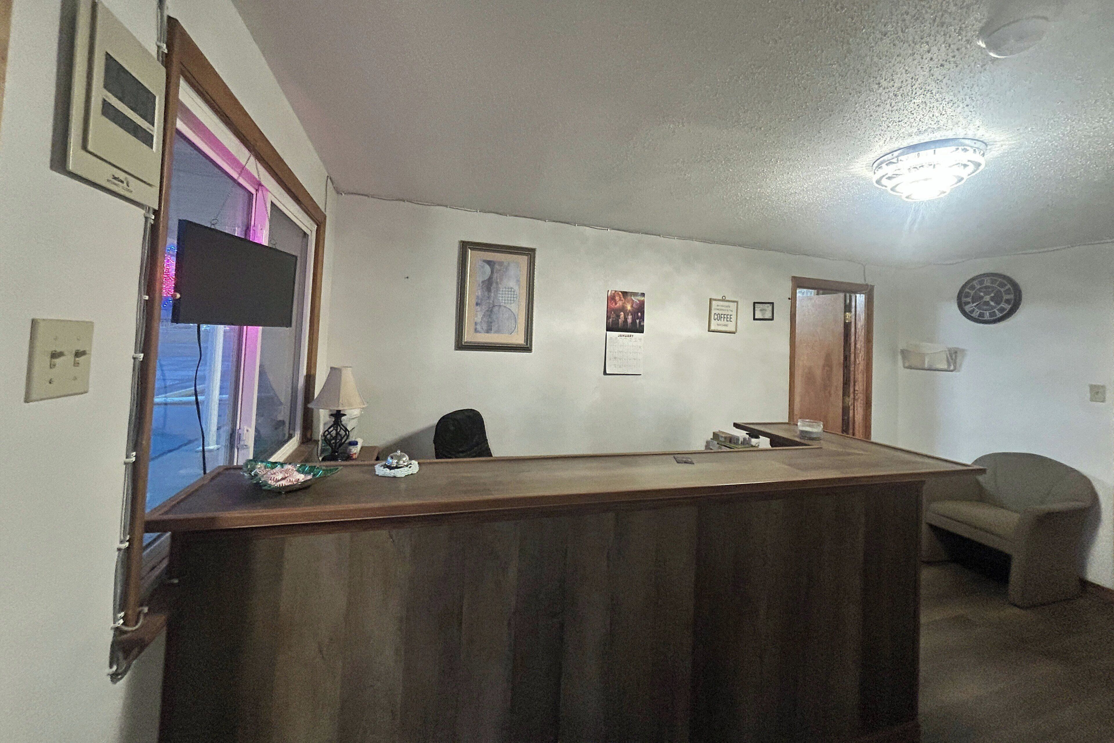 Un mostrador de recepción con un reloj, cuadros enmarcados y una lámpara.