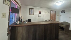 A reception desk with a clock, framed pictures, and a lamp.