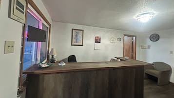 Un mostrador de recepción con un reloj, cuadros enmarcados y una lámpara.