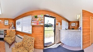 A room with a wooden interior, a reception desk, a sofa, and a chair. - Motel 8 (Olds)