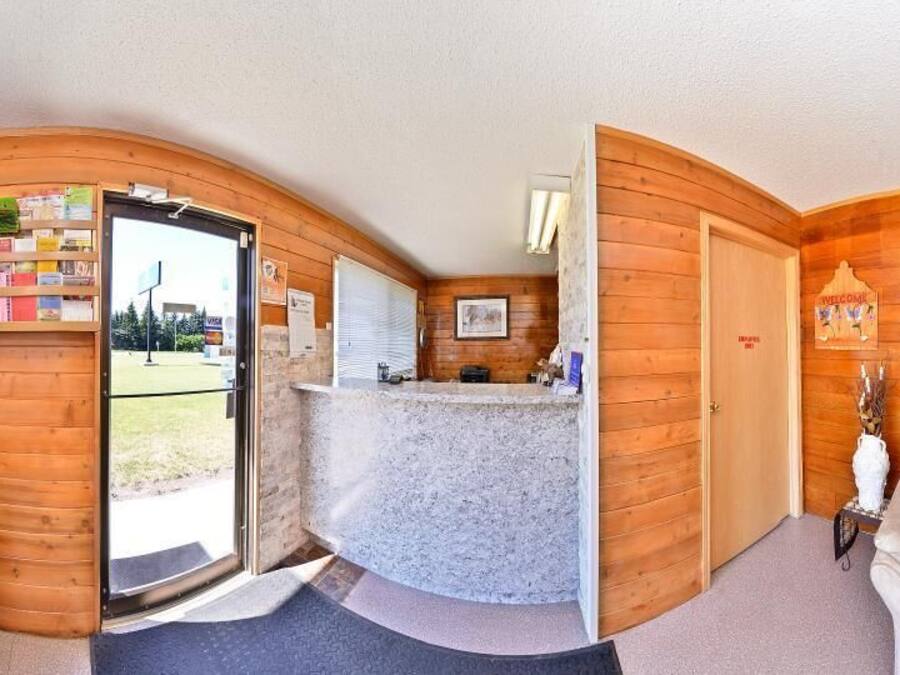 A room with a wooden interior, a reception desk, a sofa, and a chair.