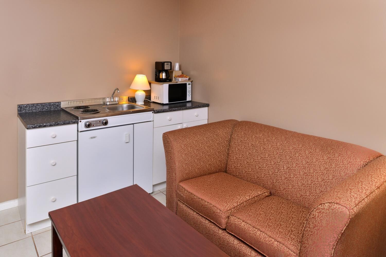 A compact kitchenette with a microwave, coffee maker, and a small table.