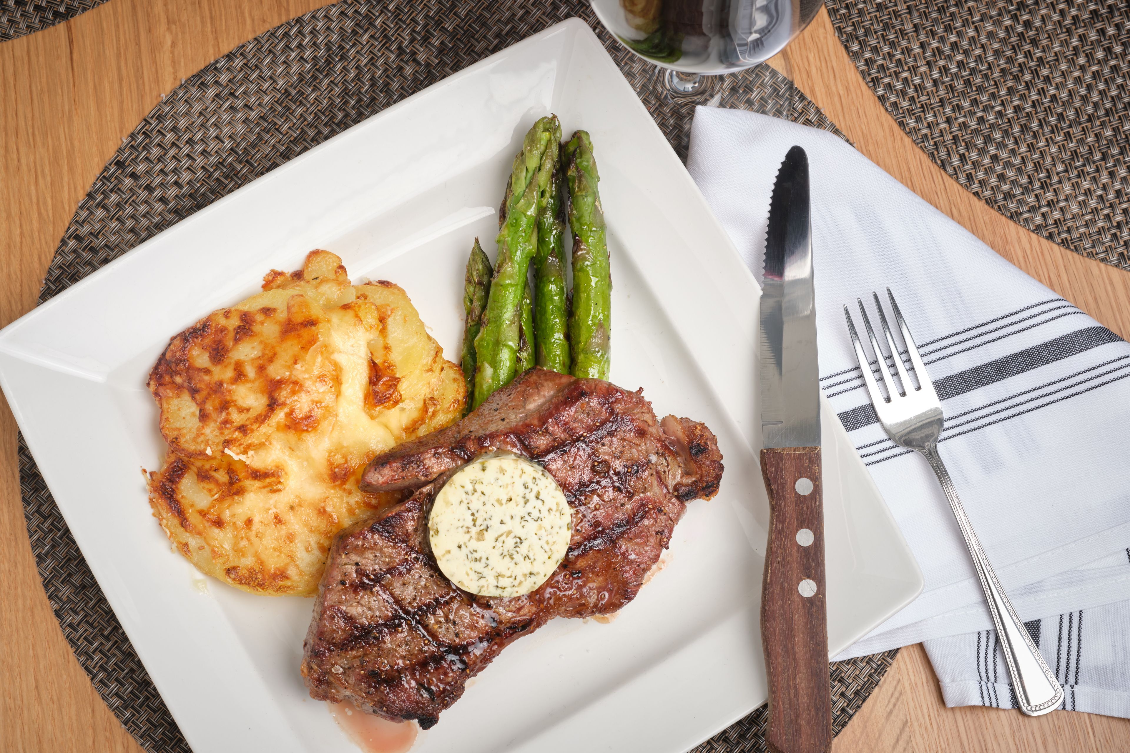 A plate with steak, asparagus, and potatoes on a table with a knife and fork.
