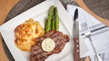 A plate with steak, asparagus, and potatoes on a table with a knife and fork.