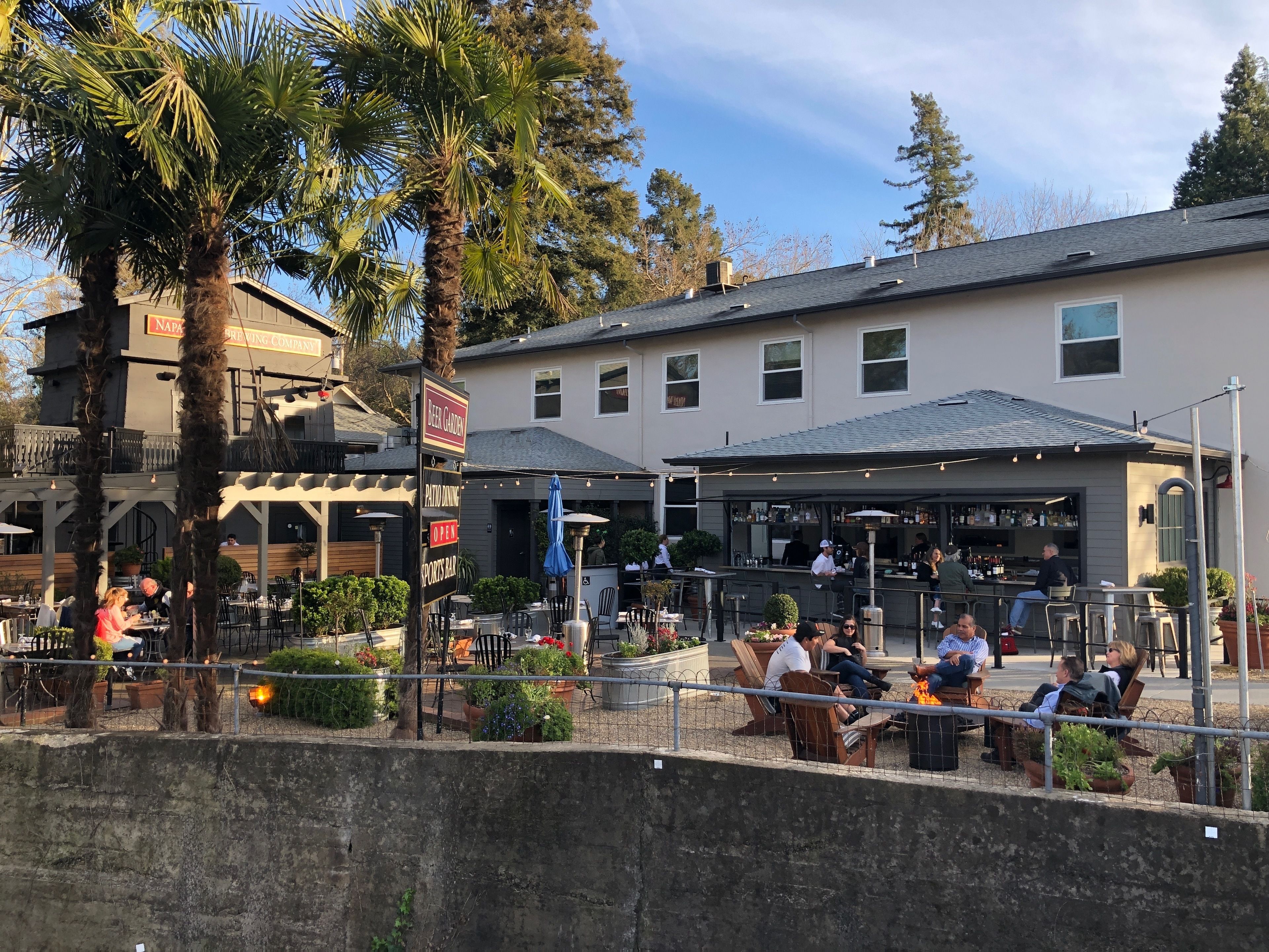 Un espacio al aire libre con mesas y sillas, un bar y un letrero para un jardín de cerveza.