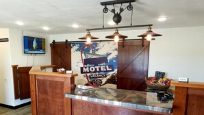 A reception desk with a wooden finish, a 'Motel Vacation' sign, and a menu board.