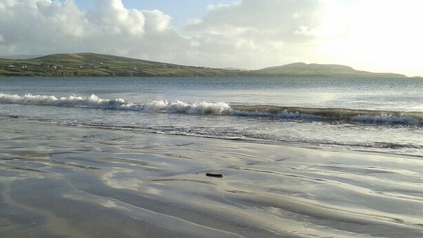 Una playa con arena mojada y olas suaves.