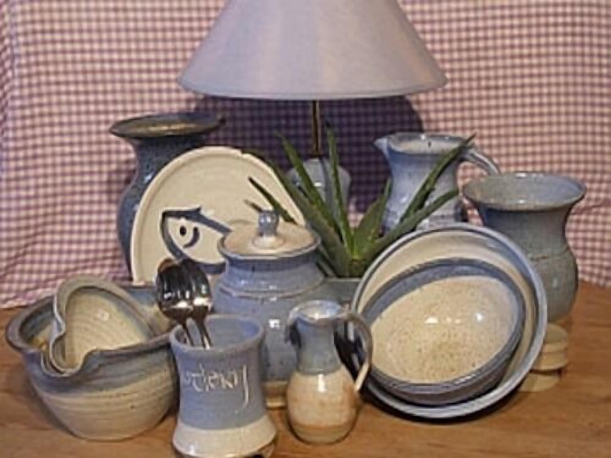 A collection of ceramic kitchenware including bowls, a jug, and a plate, arranged on a table with a checkered tablecloth.