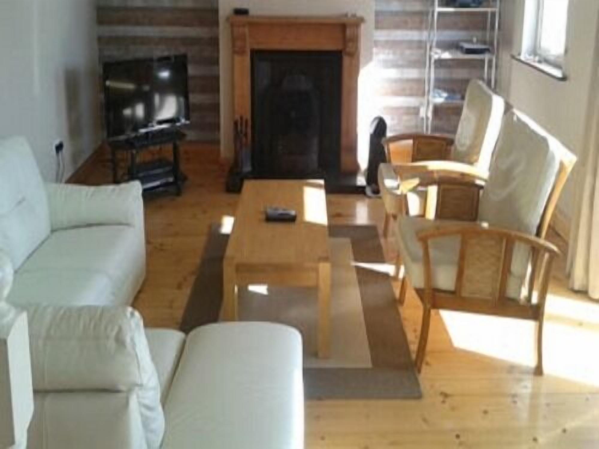 Una sala de estar con sofá, sillones, una mesa de centro y chimenea.