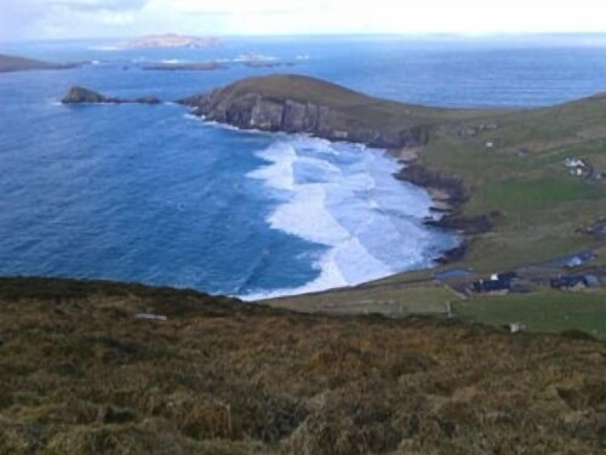 A coastal landscape with a rugged coastline, grassy terrain, and a view of the sea.