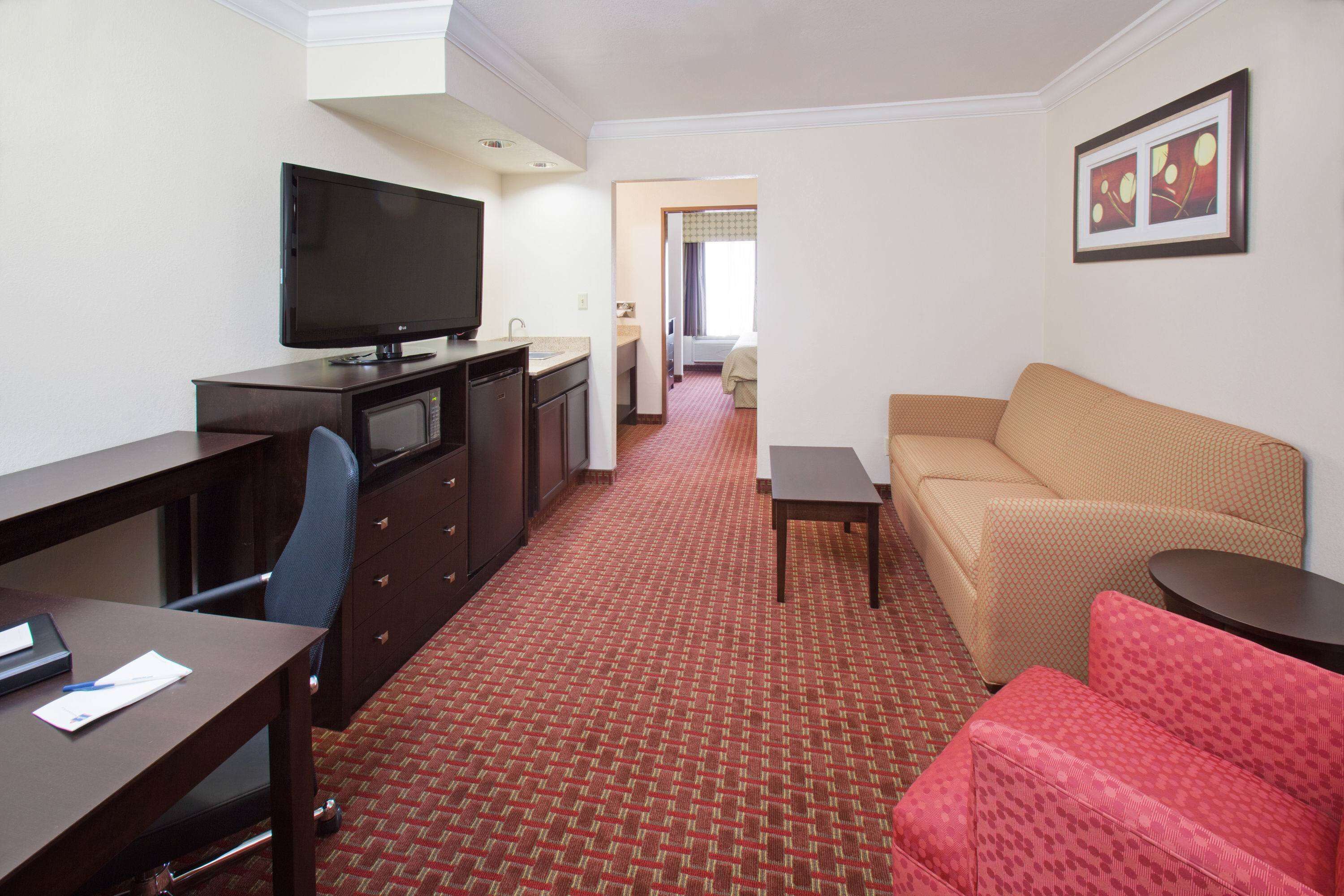 Ett hotellrum med TV, skrivbord, stol, soffa och ett litet bord.