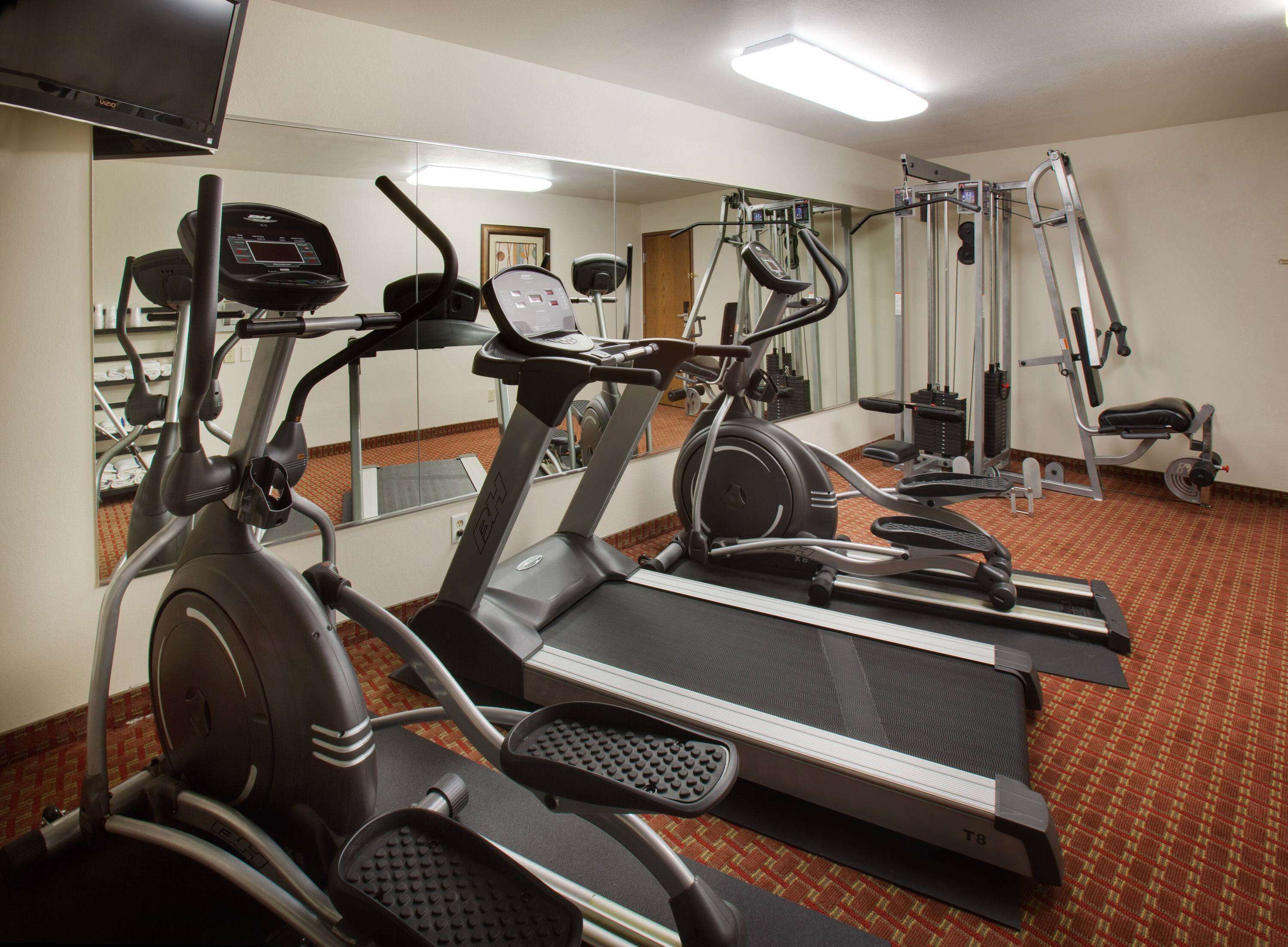 Une salle de sport équipée de tapis de course, de vélos elliptiques et d'appareils de musculation.
