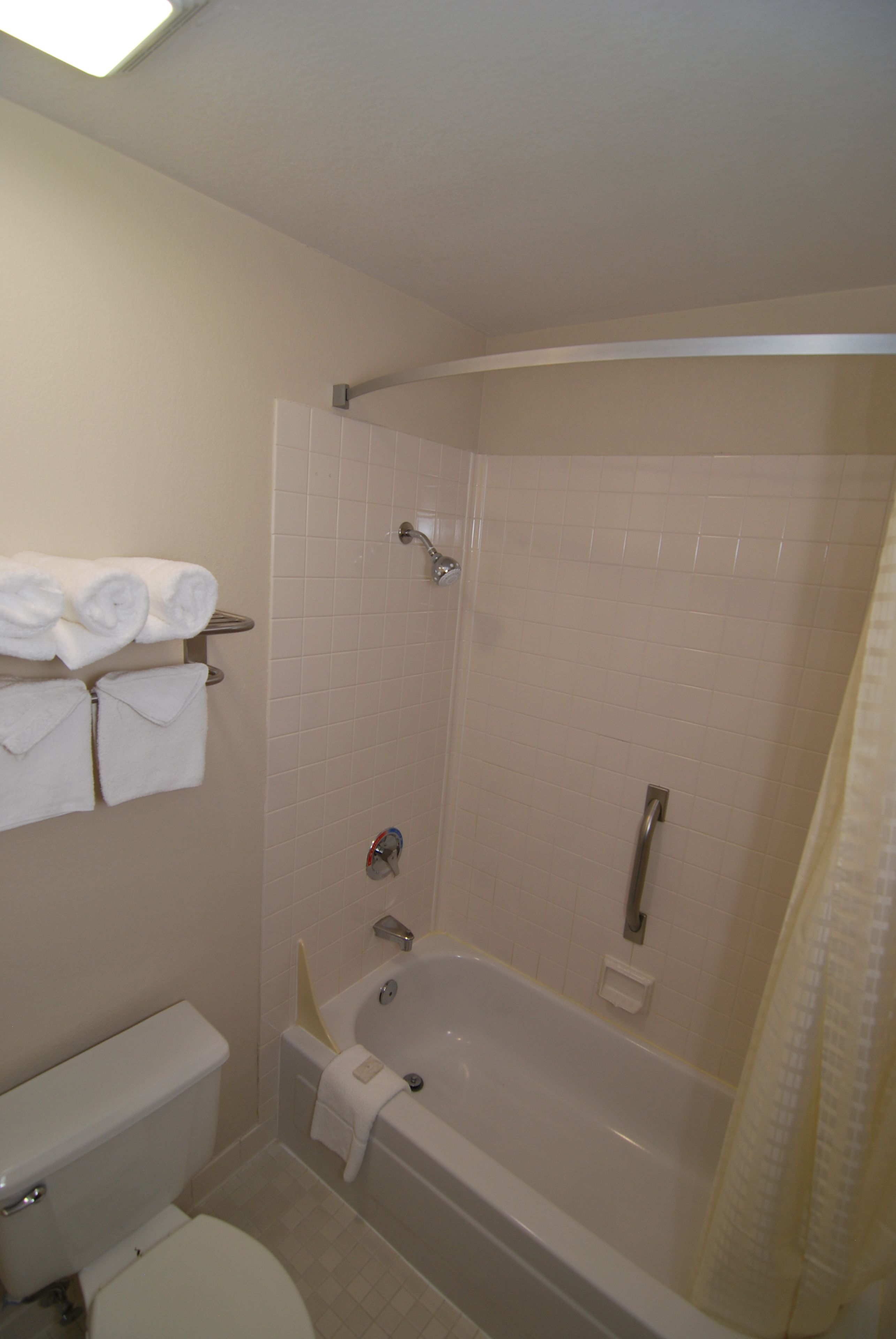 A bathroom with a bathtub, toilet, and towel rack.