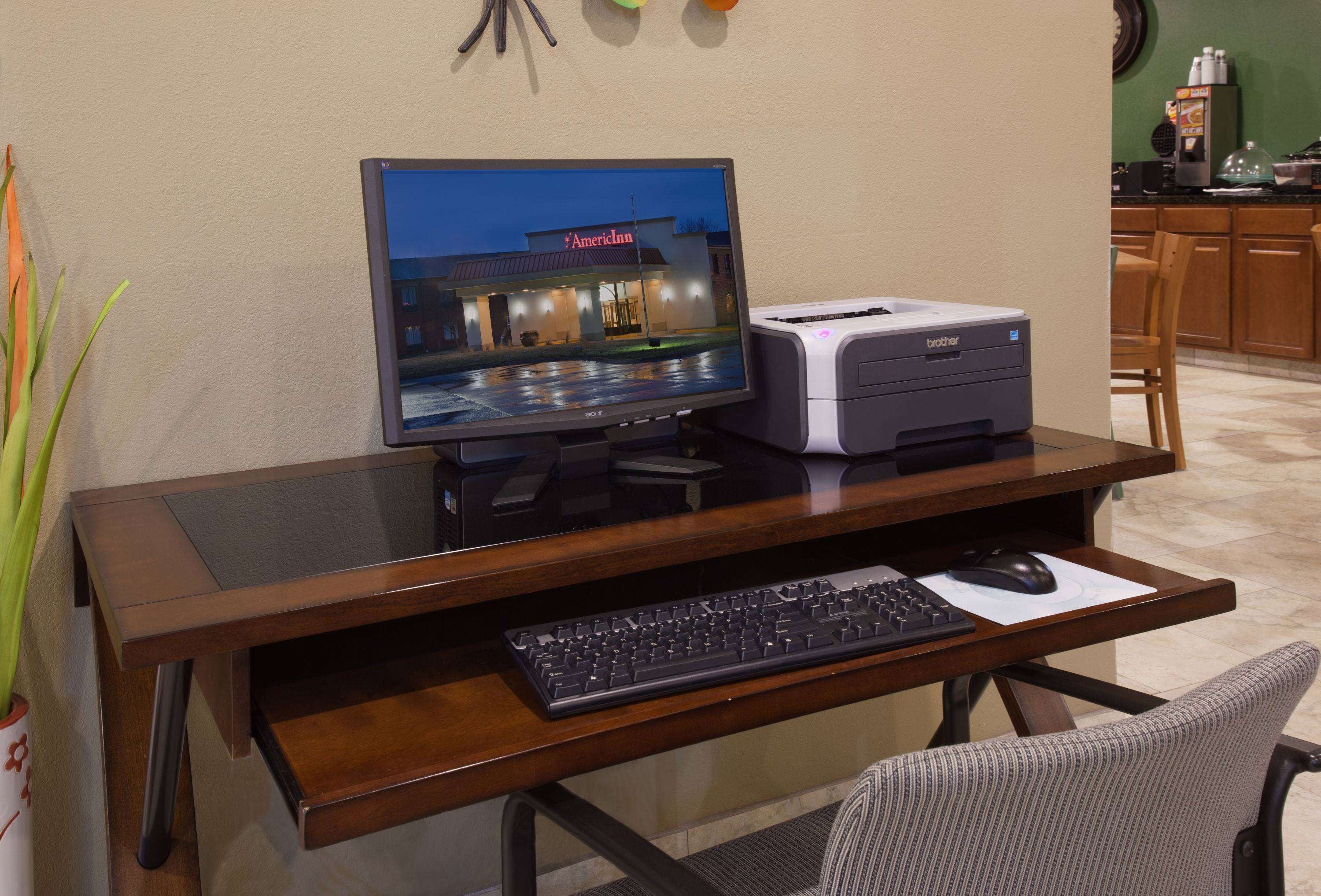 Un bureau en bois avec un écran d’ordinateur, un clavier et une imprimante.