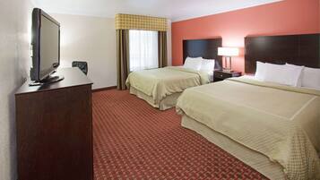 A hotel room with two beds, a TV, a desk, and a window with curtains.