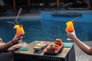 A poolside dining table with a drink, fried food, and small dishes. - Casa Andina Select Pucallpa (Callería)