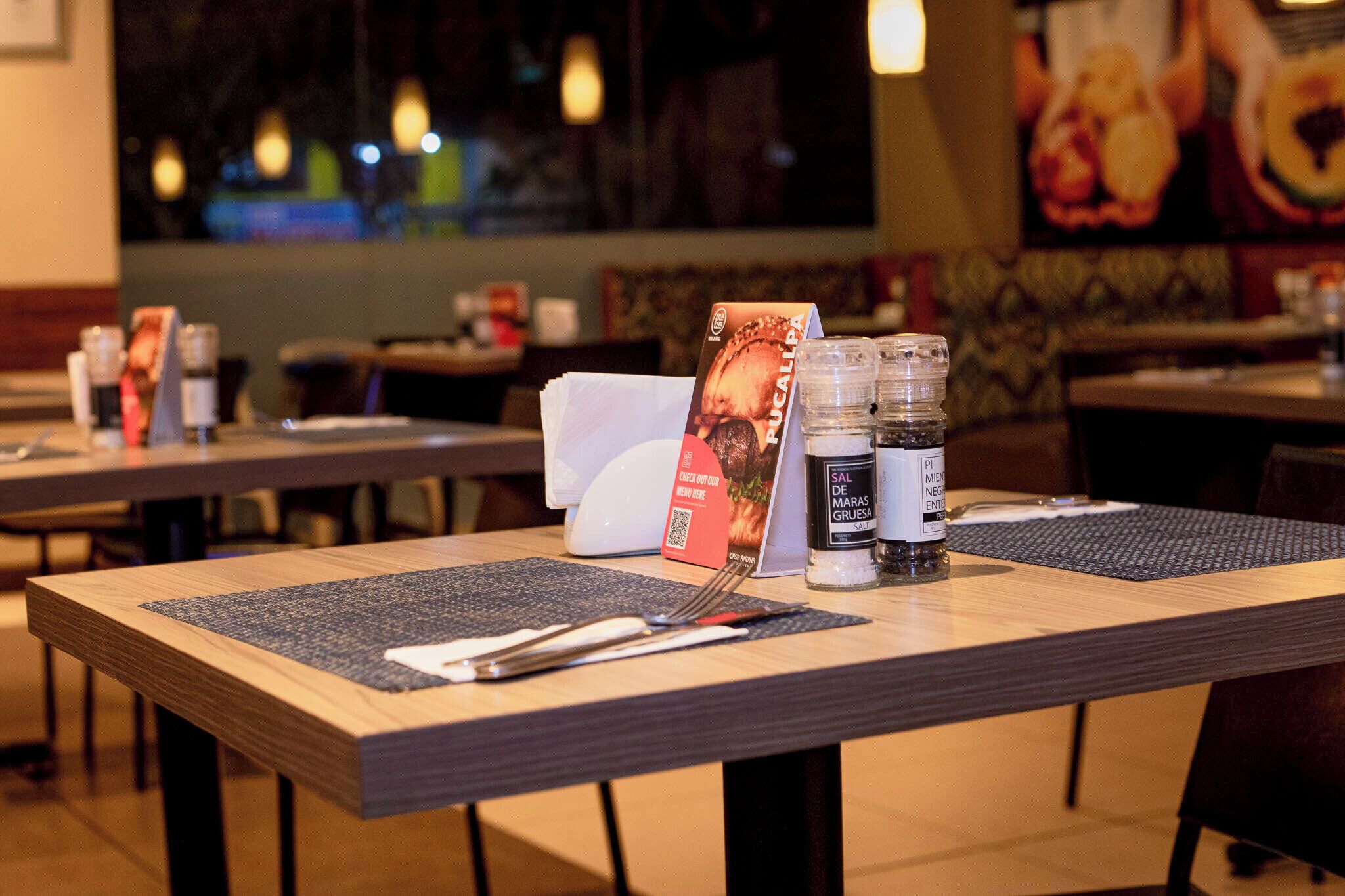 Un ambiente de restaurante con mesas preparadas para comer, menús y aderezos.