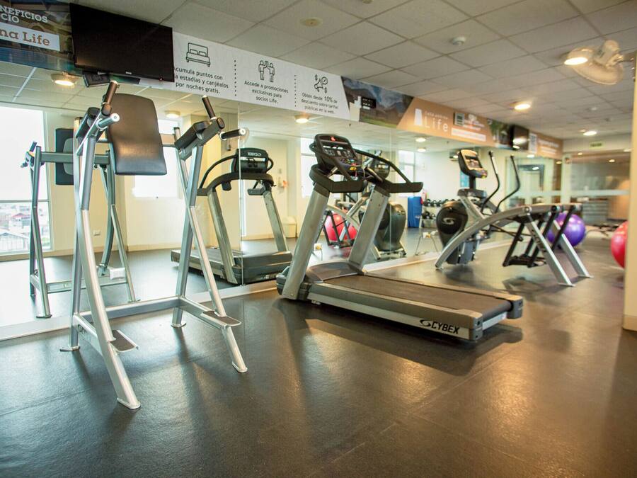 Un gimnasio con cintas de correr, elípticas y otros equipos de cardio.