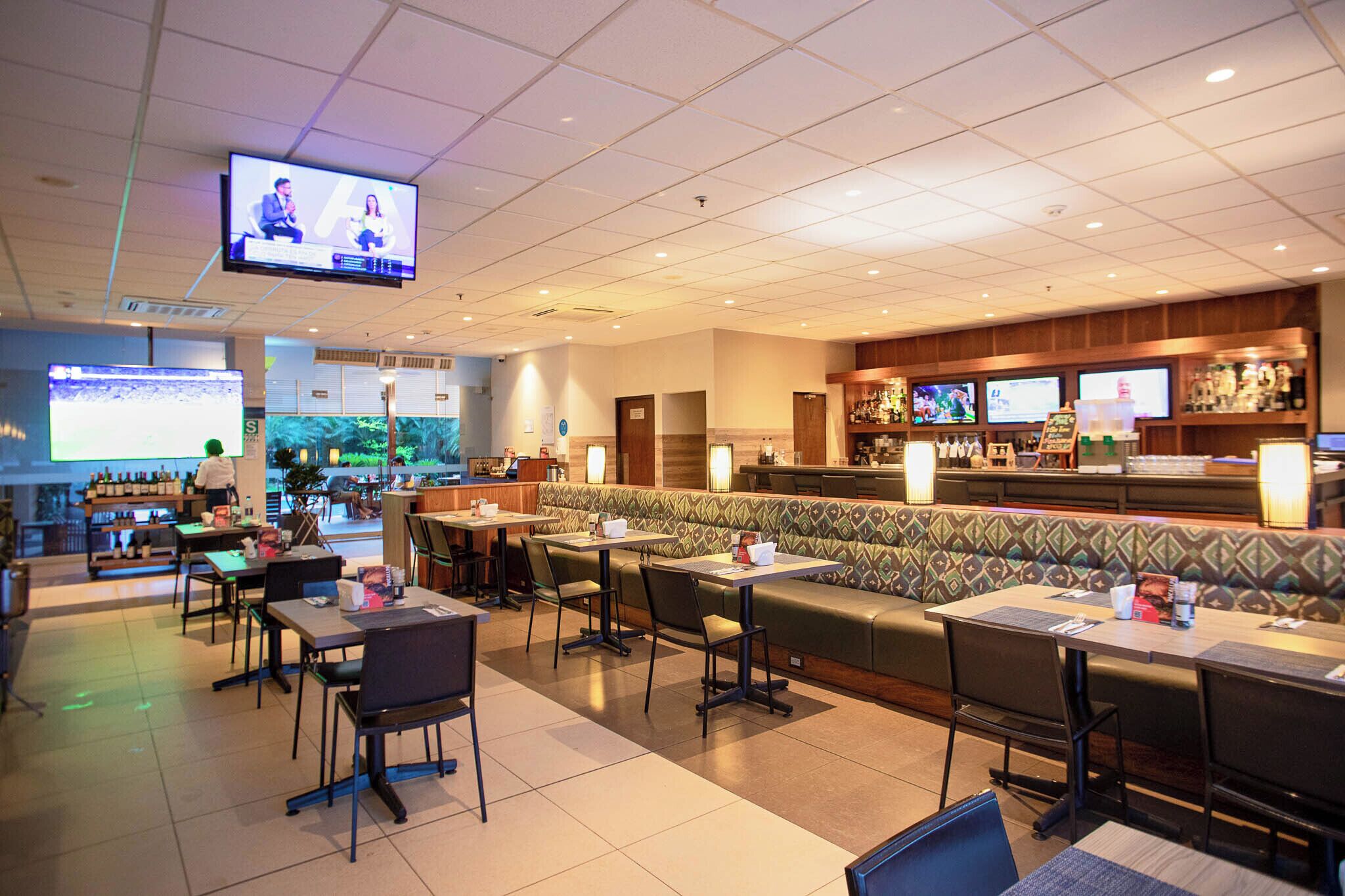 Un restaurante con cabinas, mesas y una zona de bar.