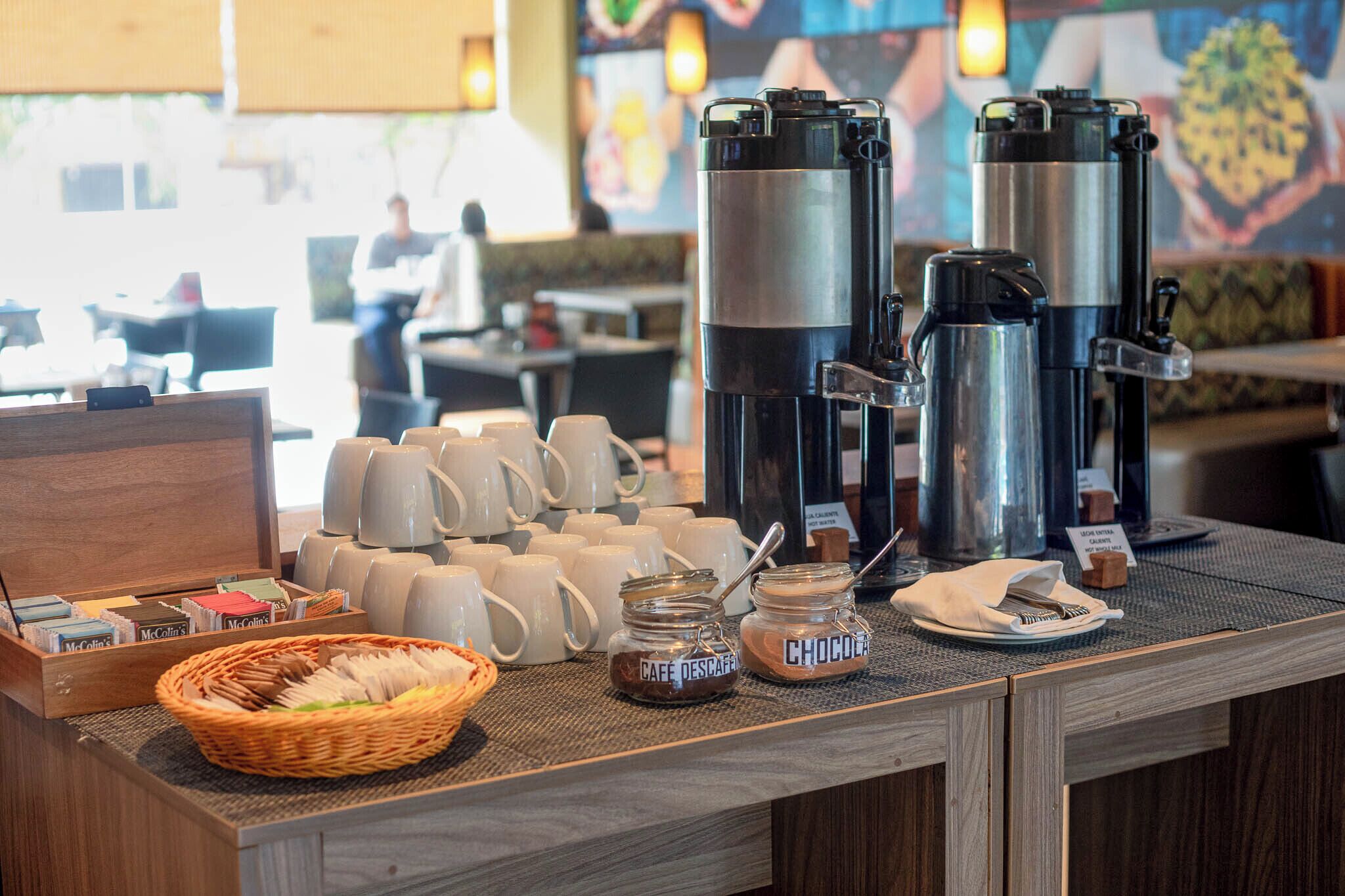 Ein Frühstücksbuffet mit Kaffeeautomaten, Tassen und Beilagen.