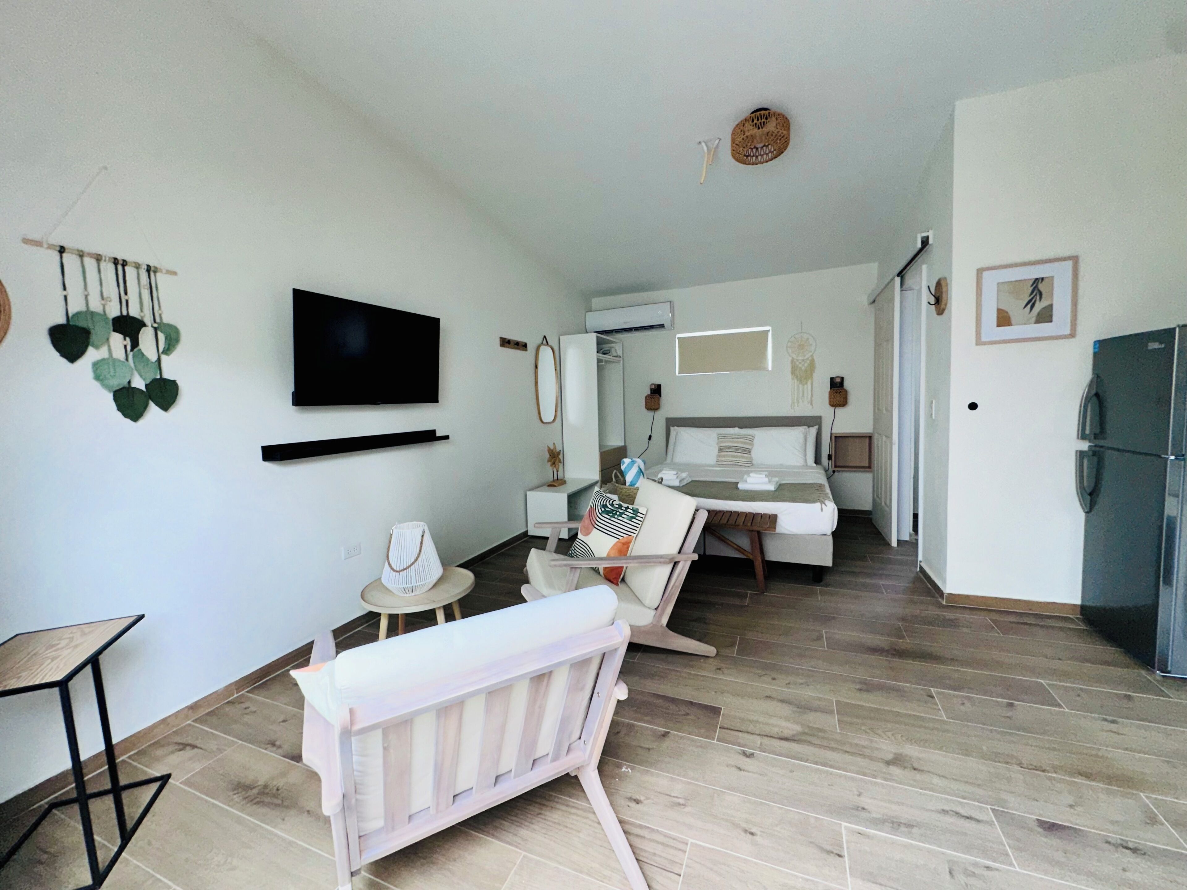 A modern, well-lit room with a bed, bedside table, and a TV mounted on the wall.