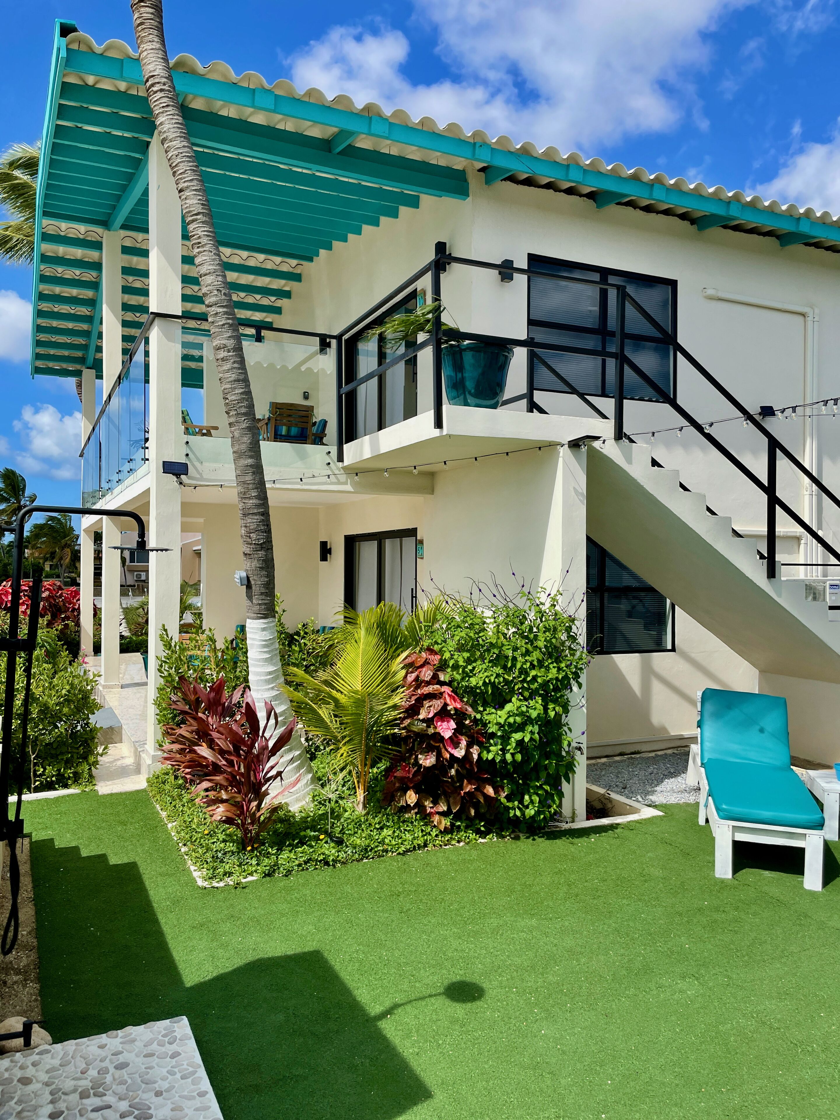 A two-story building with a balcony, a staircase, and a pool area.