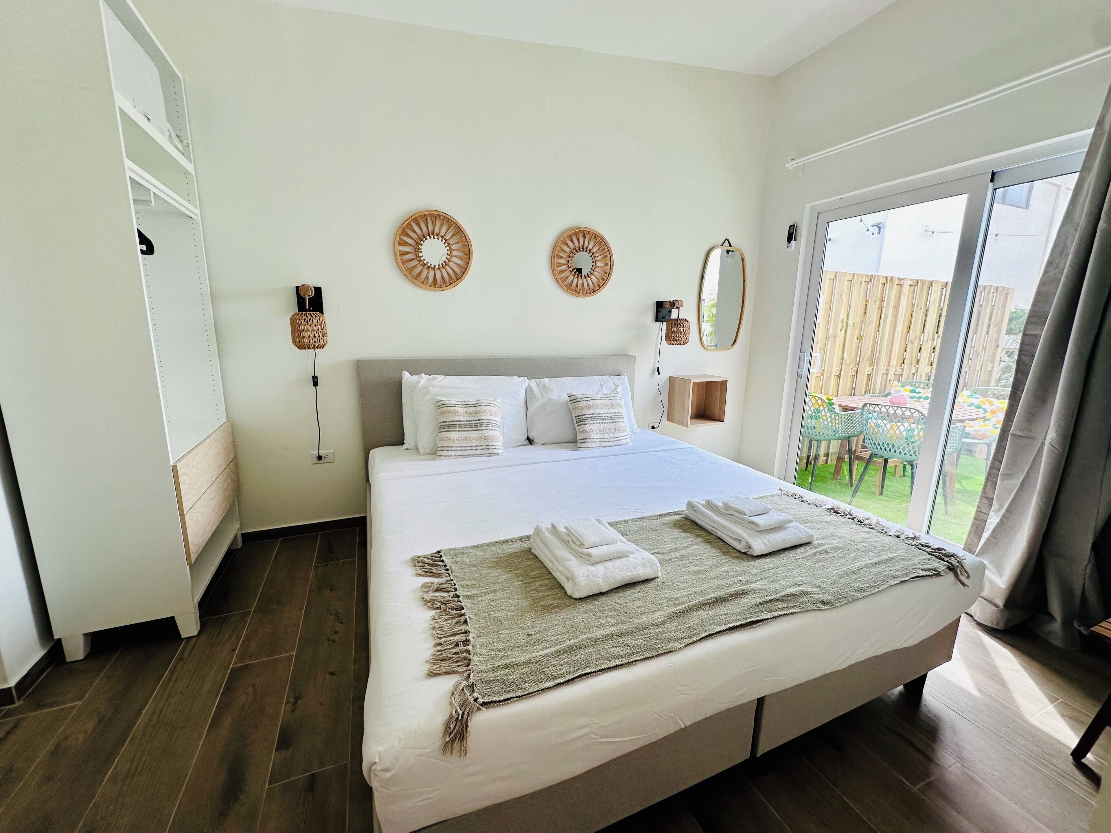 Quarto com cama, guarda-roupa, espelho e vista para o exterior.