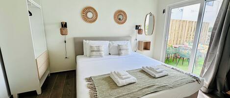 Quarto com cama, guarda-roupa, espelho e vista para o exterior.