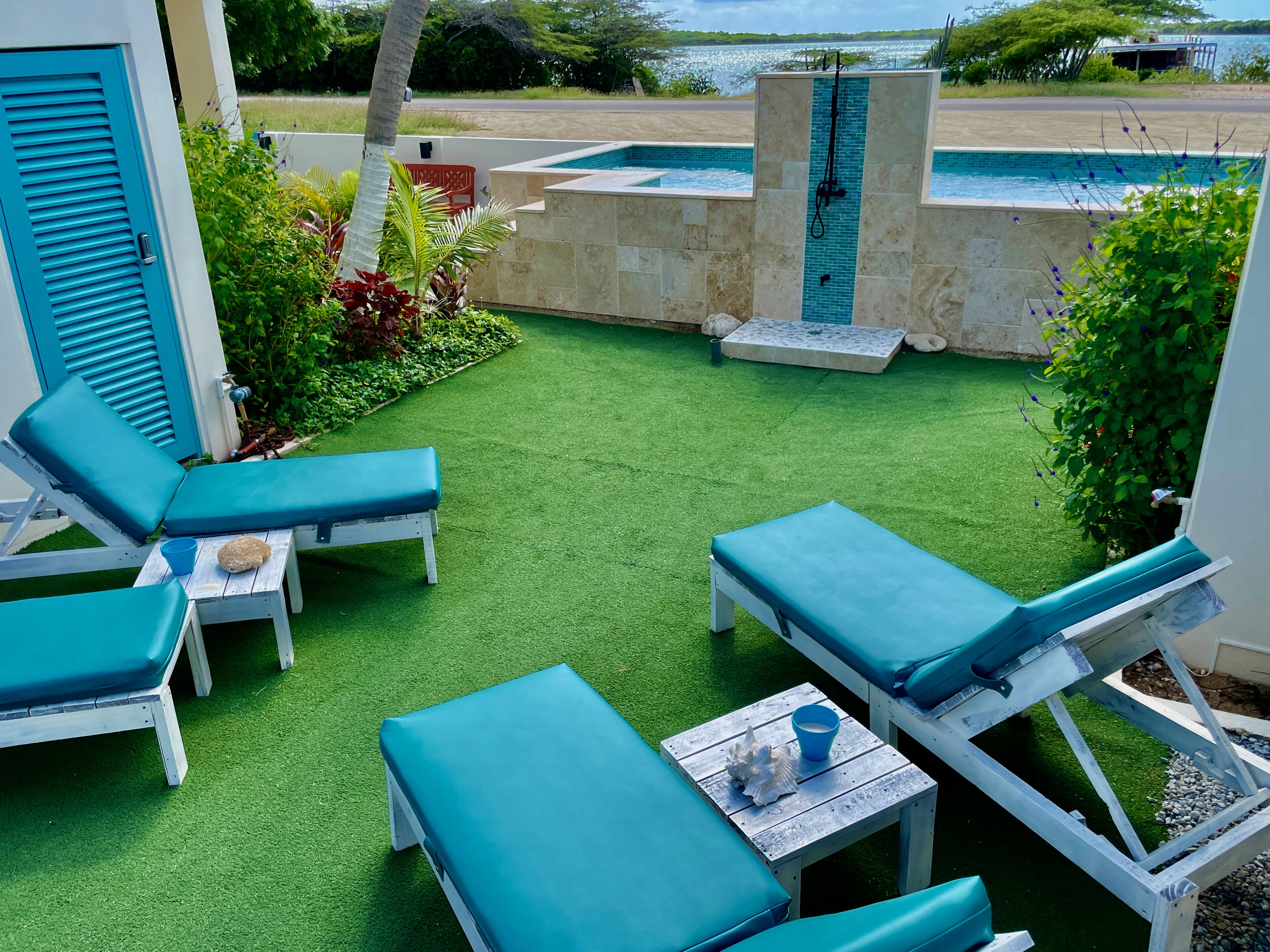 A poolside area with blue lounge chairs and a small table with a cup and shell decoration.