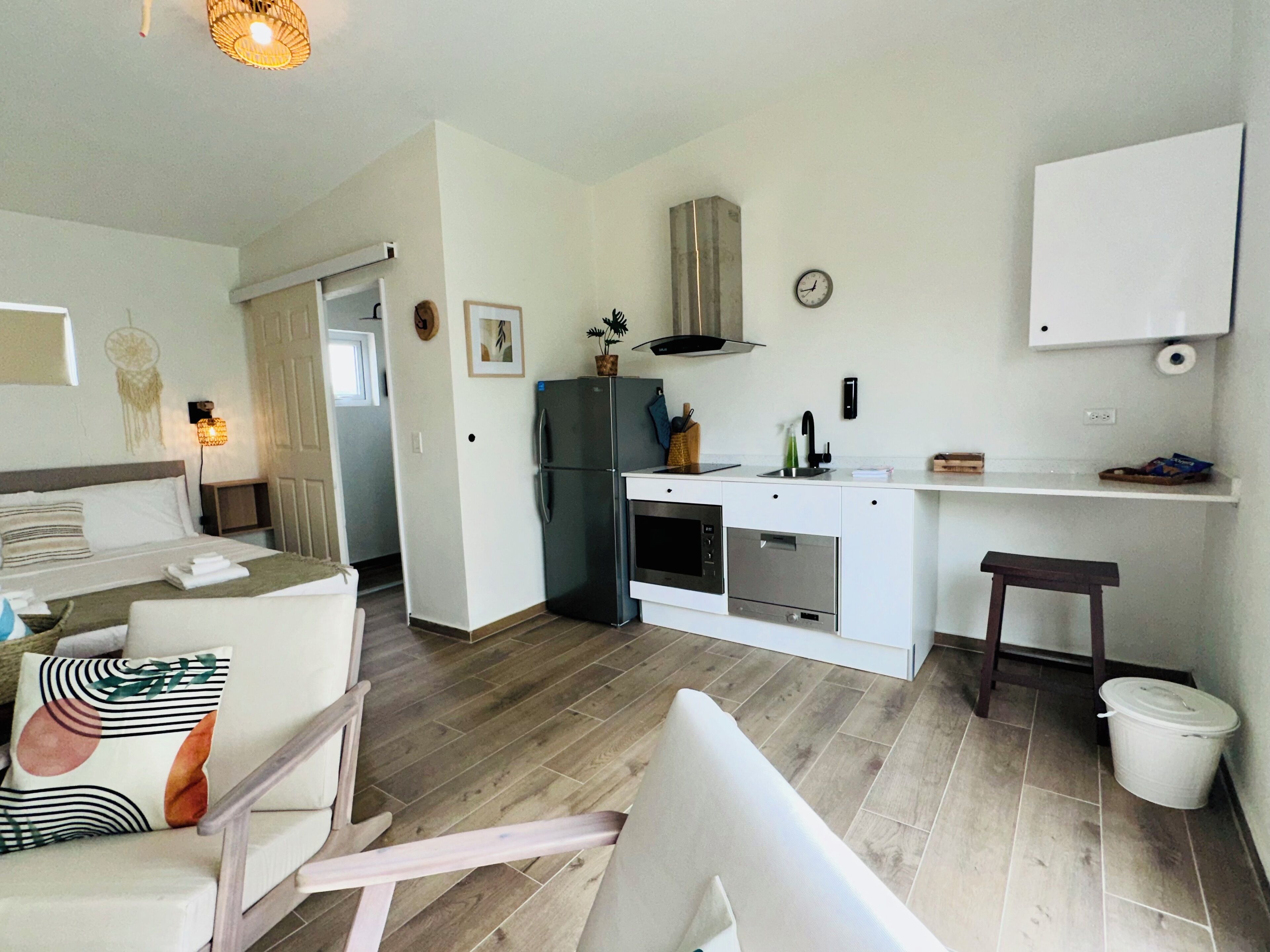 Eine kompakte, moderne Wohnung mit Küchenzeile, Essbereich und Schlafzimmer.