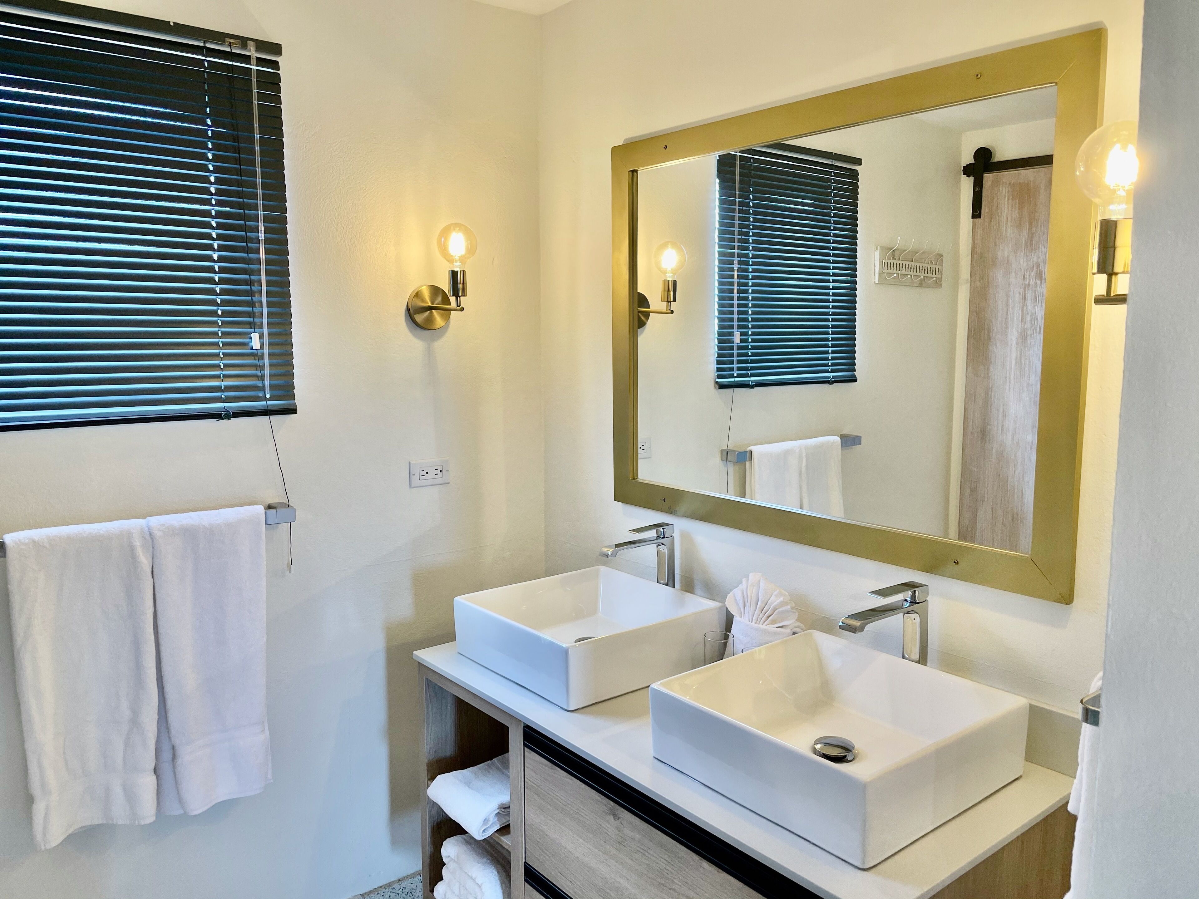 A modern bathroom with two sinks, a large mirror, and a towel rack.