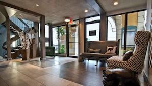 Un hall amplio con una escalera moderna, un sillón de cuero y un banco.