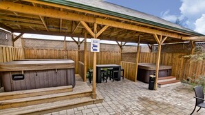 Un espacio al aire libre techado con bancos de madera y jacuzzis.