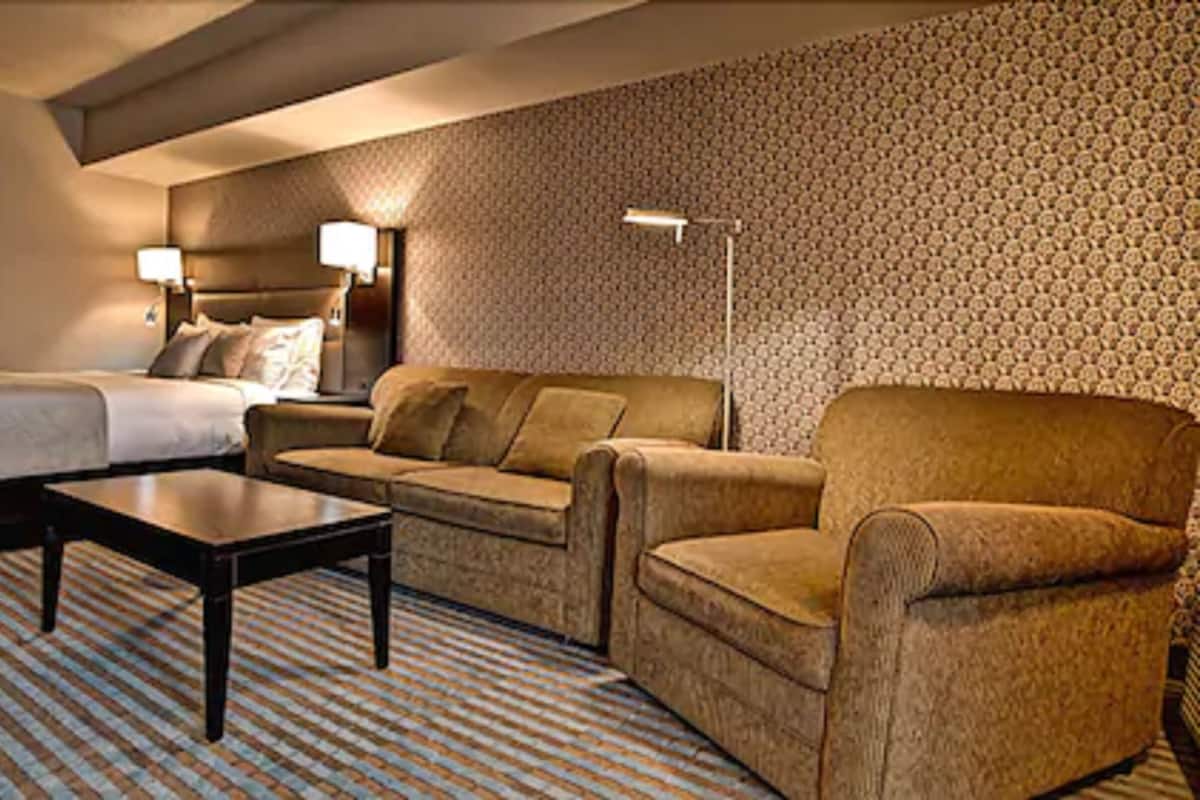 Una habitación de hotel con cama, sofá, sillón y una mesita.