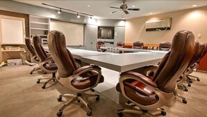 Una sala de conferencias con una larga mesa, sillas de cuero, un ventilador de techo y un equipo de aire acondicionado.