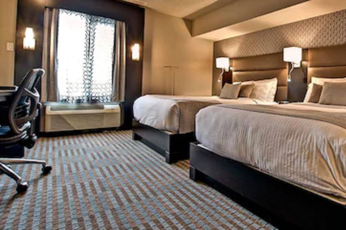 Habitación de hotel con dos camas, un escritorio y una silla.
