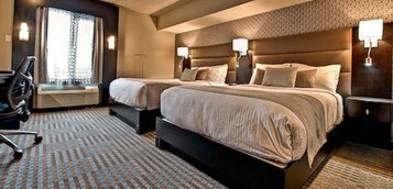 A hotel room with two beds, a desk, and a chair.